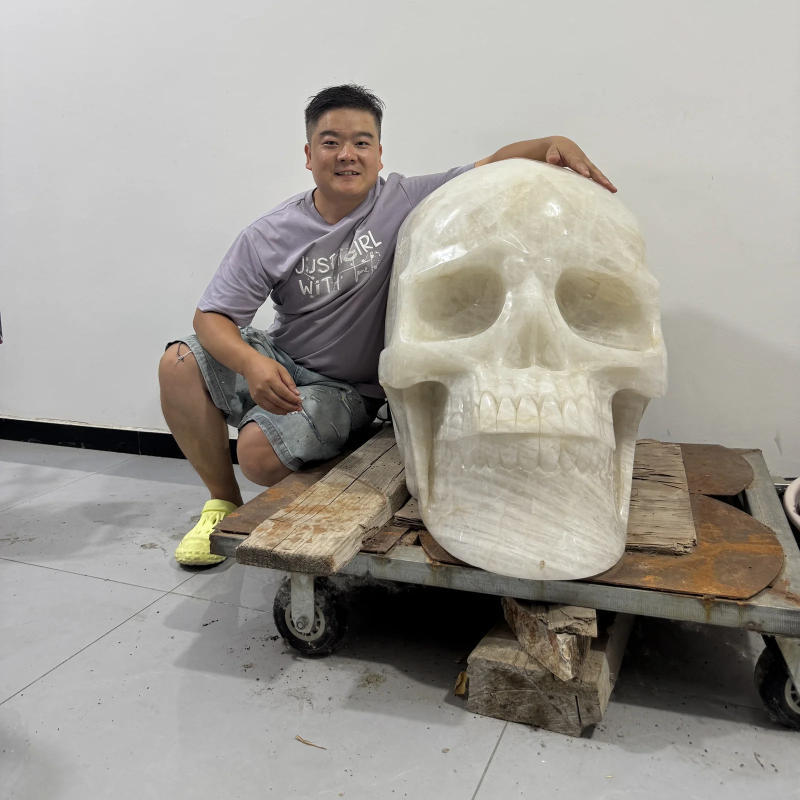 A person seated beside a large crystal skull carving